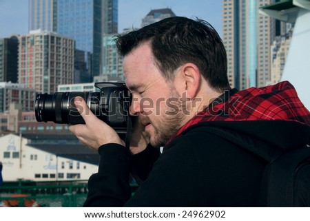 A photographer on the ferry boat with Seattle, Washington in the background.