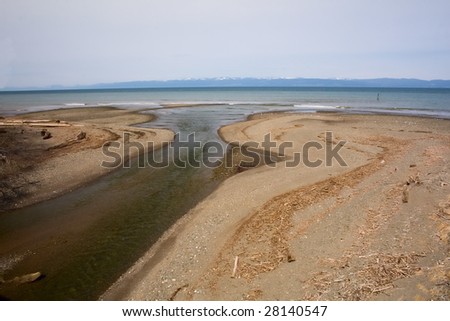 The mouth of a small river opening up into Puget Sound, Washington, with Victoria Island, Canada in the distance.