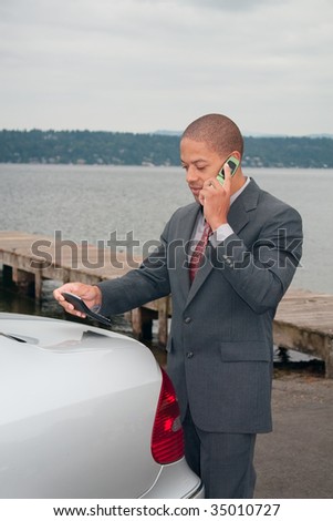 A young ethnic businessman speaks on his cellphone and consults the calculator as he makes the deal.