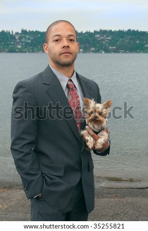 A young successful businessman and his Yorkshire terrier dog on the lake shore.