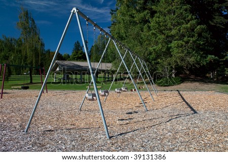 A large toddler swing set in a beautiful park over bark mulch for safety.