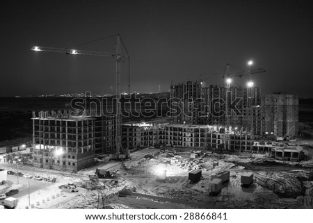 Building area . Night work of elevating crane . Industry scene . Black and white photo