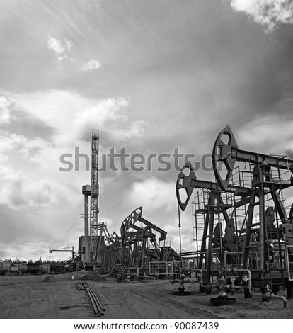 Oil and gas industry. Work of oil pump jack and rig on a oil field. Mining and drilling. Black and white photo