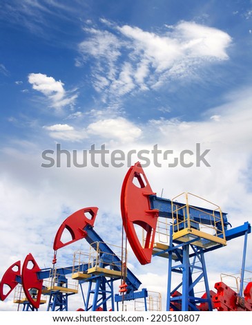 Gas and oil industry. Work of oil pump jack on a oil field. Blue sky and white clouds