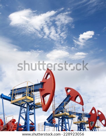 Gas and oil industry. Work of oil pump jack on a oil field. Blue sky and whitee clouds.
