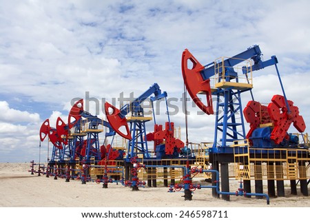 Gas and oil industry. Work of oil pump jack on a oil field. White clouds, blue sky, desert