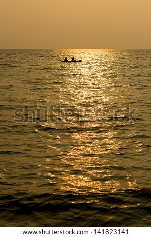 Silhouette single boat at sea in sunset, two persons on a boat at middle sea.