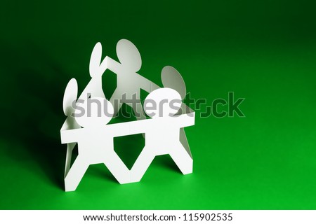 Team of Paper Dolls holding Hands on Green Background