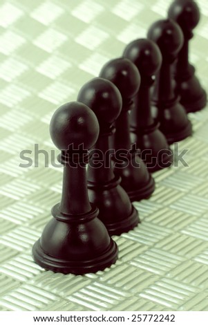 Row of black pawns arranged on off white metallic background