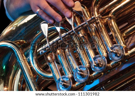 Brass instrument with musician hand in stage lights