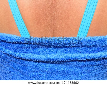 Back of woman wearing blue swimsuit and towel