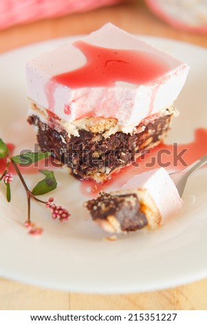 Raspberry mousse cake with biscuits and coca. Presented on white plate with silver fork. Ingredients:flour, biscuits, cocoa, creme, sugar, butter, raspberries, raspberry sauce.