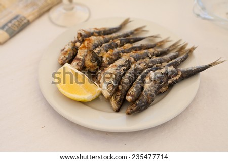 Fresh smoked sprats shown on a white plate with lemon piece. Fresh sea food. Organic food. Seaside, holidays. Light supper. Diet. Omega 3.