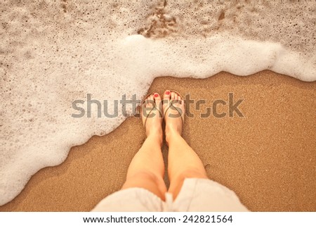 Sea foam, waves and naked feet on a sand beach. Holidays, relax, nature.