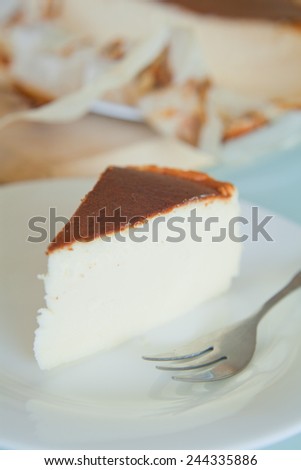 Piece of vanilla cheesecake with crashed biscuits on the top. Cheesecake was prepared with flour, white cheese, white sugar, vanilla sugar, eggs and butter. Presented on white plate.