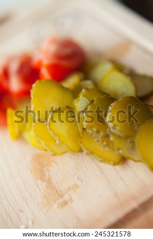 Pickled cucumber and cherry tomato cut into pieces presented on a wooden desk. Healthy food. Preparation for breakfast. MAcro perspective. Nobody. Food and meal at home.