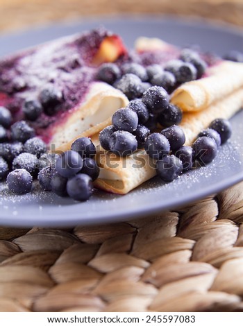 Thin pancake rolls, roast without fat, wraped with white cheese. They were sprinkled with blueberries and white powered sugar.