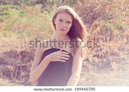 Sensual portrait of a girl in a black dress in the forest