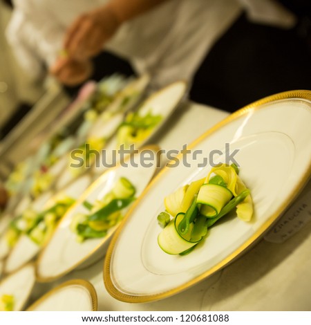 Preparation of the vegetables in the kitchen. Meal for a lot of people. White and gold plates ready to be served.
