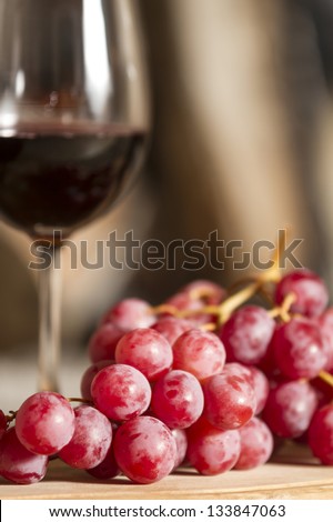 grapes and a cup of wine over a wooden table.