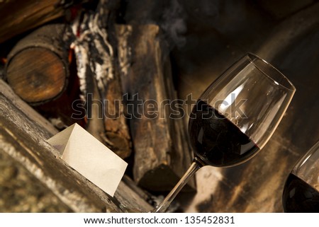Wine cups, cork, bottle of wine, wood, grapes and fire on the background.