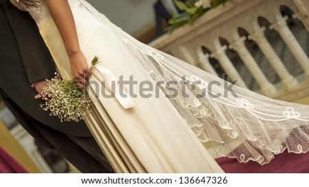 Woman in church about to get married with white dress and flowers next to the groom.