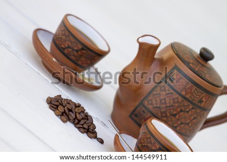 cup of coffee and beans over a wooden table with white background. Food and drinks, good smell, traditional beverage. Gastronomy. Brown bean and classic cups and spoon.