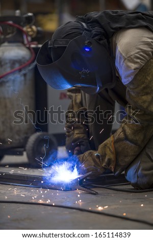 Man working with metal, welding. Sparks everywhere. Mask