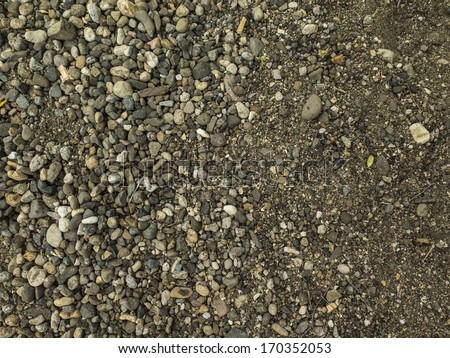 Shore soil showing a transition o rocks to sand. Gradient of texture and size of rocks. Nobody.