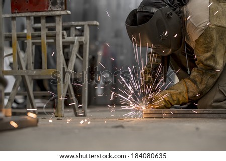 Man working on the floor, welding, with mask and gloves for protection. Handwork.