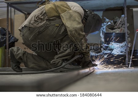 Man working on the floor, welding, with mask and gloves for protection. Handwork.