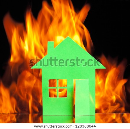 Paper house in fire on a black background concept