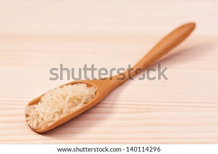 White rice in bamboo spoon on a wooden surface
