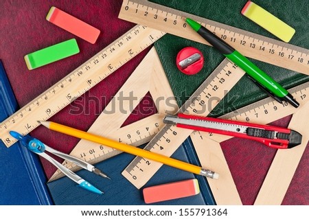 Wooden rulers with school accessories on a books covers close-up