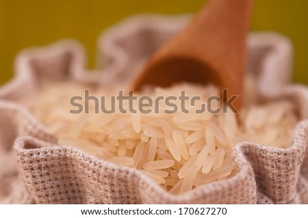 Raw rice in the jute sack with bamboo spoon close-up