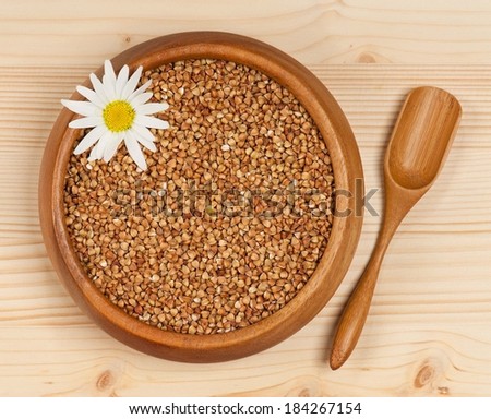 Raw buckwheat in a bamboo bowl on a wooden surface