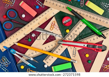 Wooden rulers with school accessories on a books covers close-up