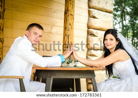 Happy bride and groom sit at a table and holding hands