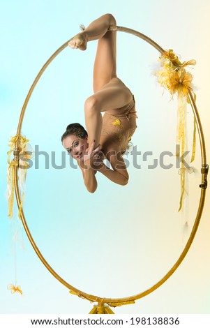Plastic beautiful girl gymnast on acrobatic circus ring in flesh-colored suit