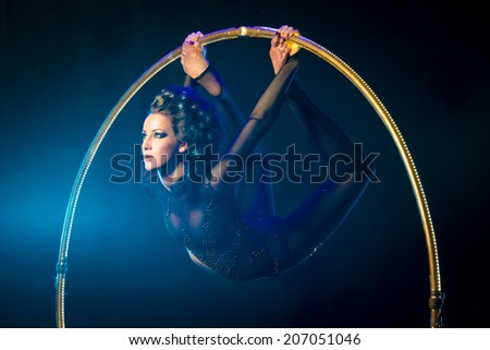 Portrait of a sexual acrobat on a dark background with a luminous gymnastic hoop.