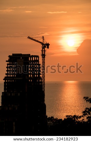 Silhouette high crane and building at construction site with the sunset time