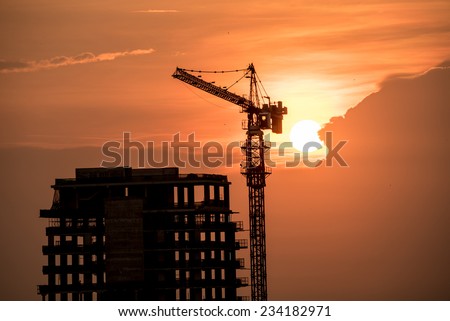 Silhouette high crane and building at construction site with the sunset time
