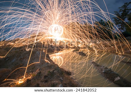 Spinning fire with steel wool in the twilight time and blue hour