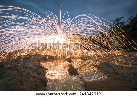 Spinning fire with steel wool in the twilight time and blue hour