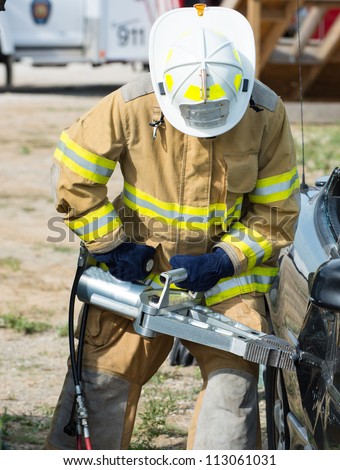 Firefighter using to the jaws of life to open a car door