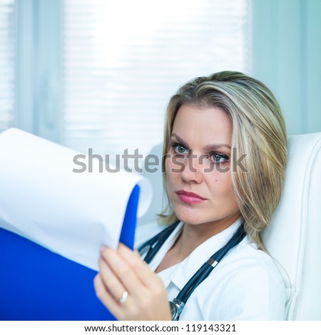 Pretty Young Female Doctor Is Studying Medical Results in Her Ambulance (color toned image)