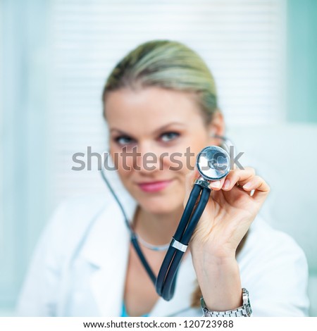 Pretty Young Female Doctor Is Holding a Black Stethoscope (shallow depth of field, color toned image)