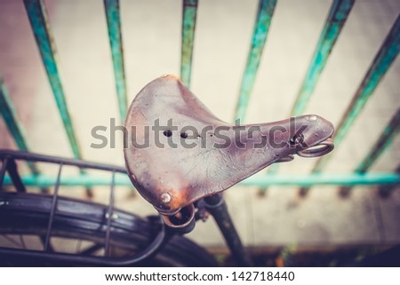 Detail of a Vintage Bike Seat with Fence Bars in the Background