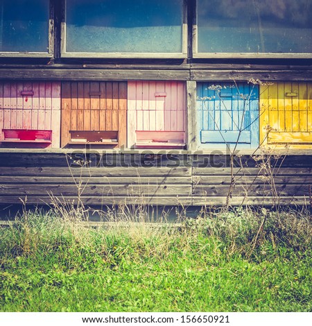 Vintage Background Made of an Old Wooden Bee House with Colorful Beehives