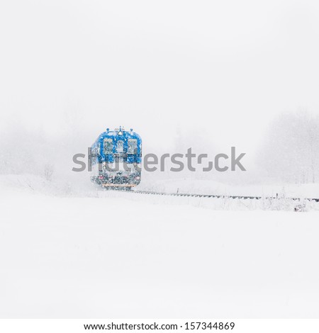 Blue Train Is Approaching on a Snow-covered Railway in Winter